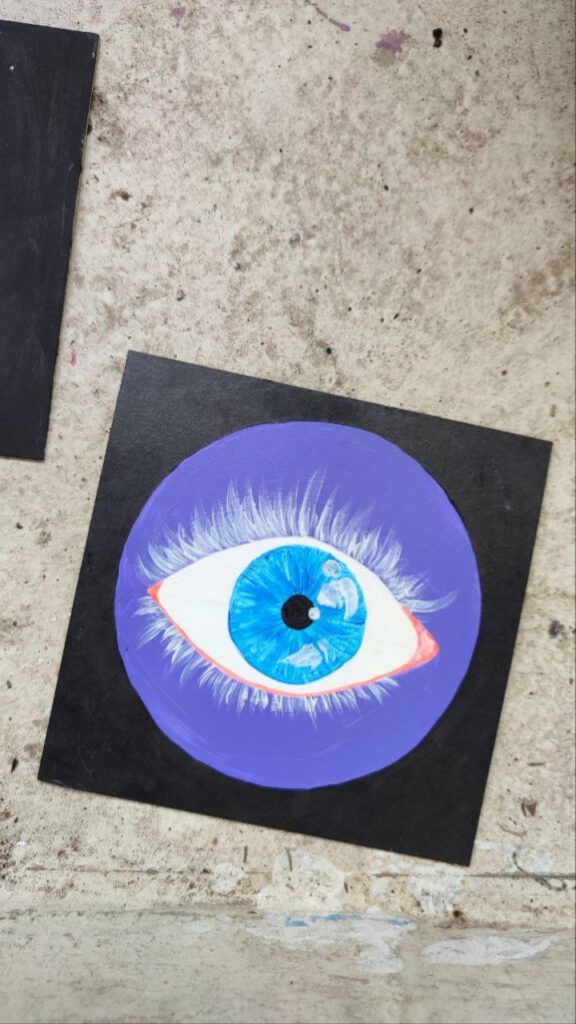 Small square painting of an eye with white lashes and blues iris. It's sitting in a purple circle with black in the background. Rather simplified style, semi-realistic.